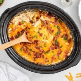 overhead shot of Crockpot Crack Chicken and Rice in a crockpot with a wooden spoon grabbing a piece