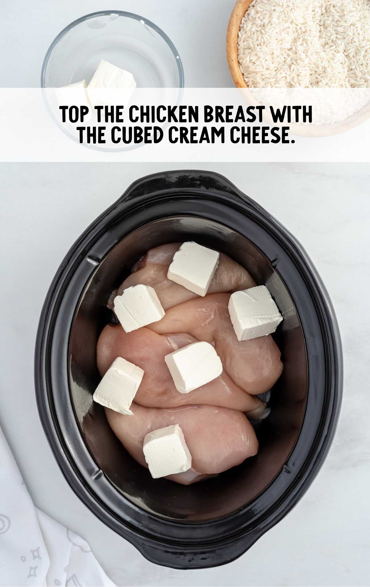 chicken breast and cubes of cream cheese in a crockpot