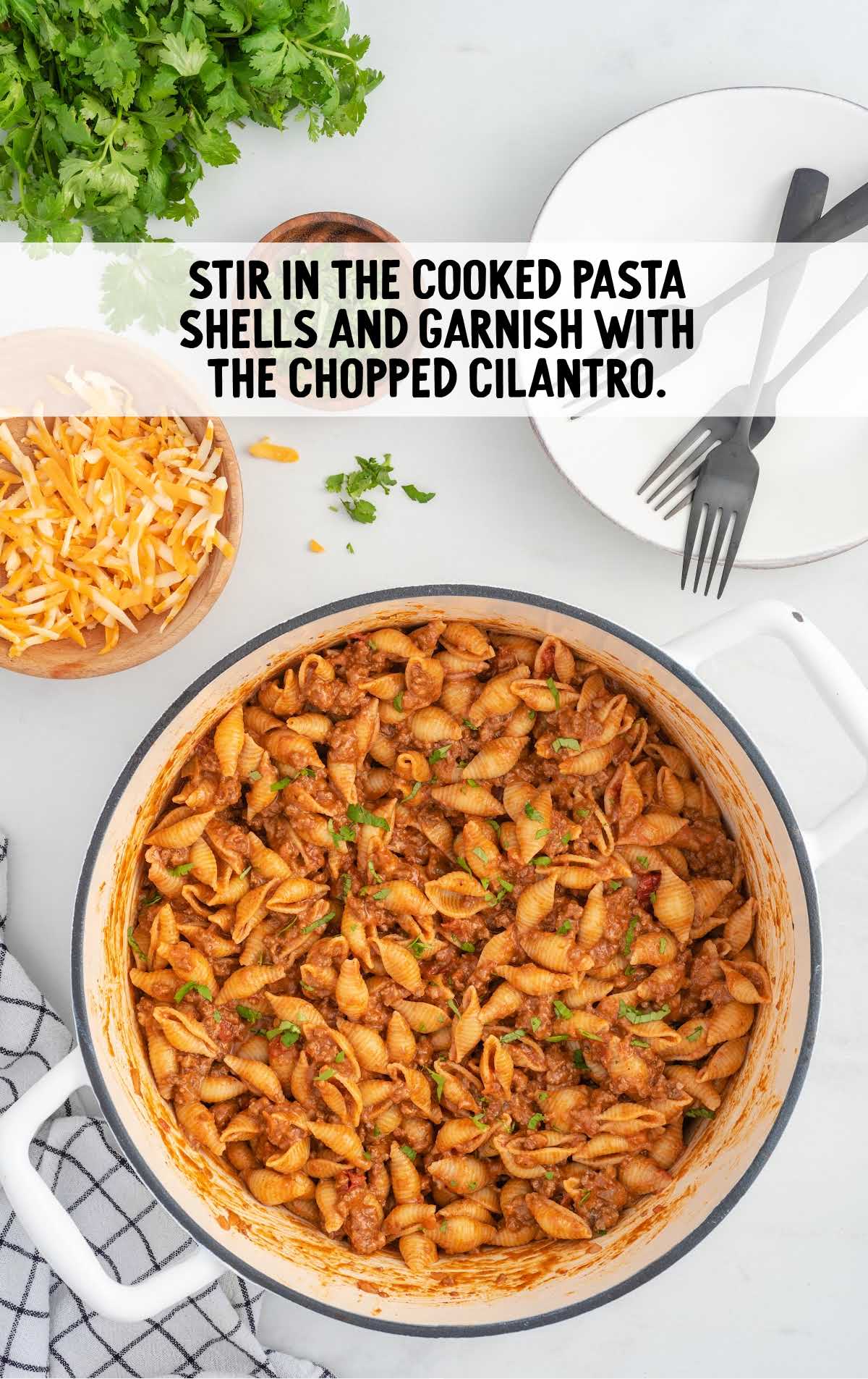 cooked pasta shells stirred and garnished with chopped cilantro in a pot
