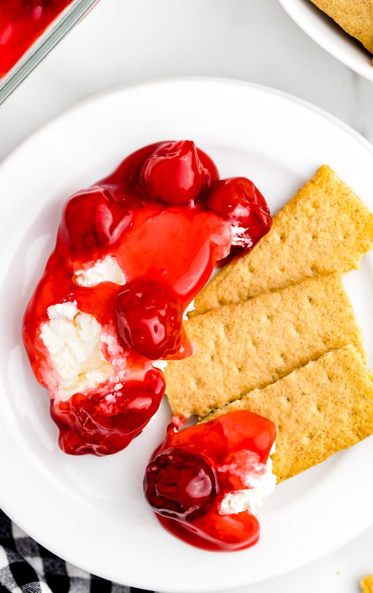 overhead shot of a piece of Cherry Cheesecake Dip with graham cracker on a plate