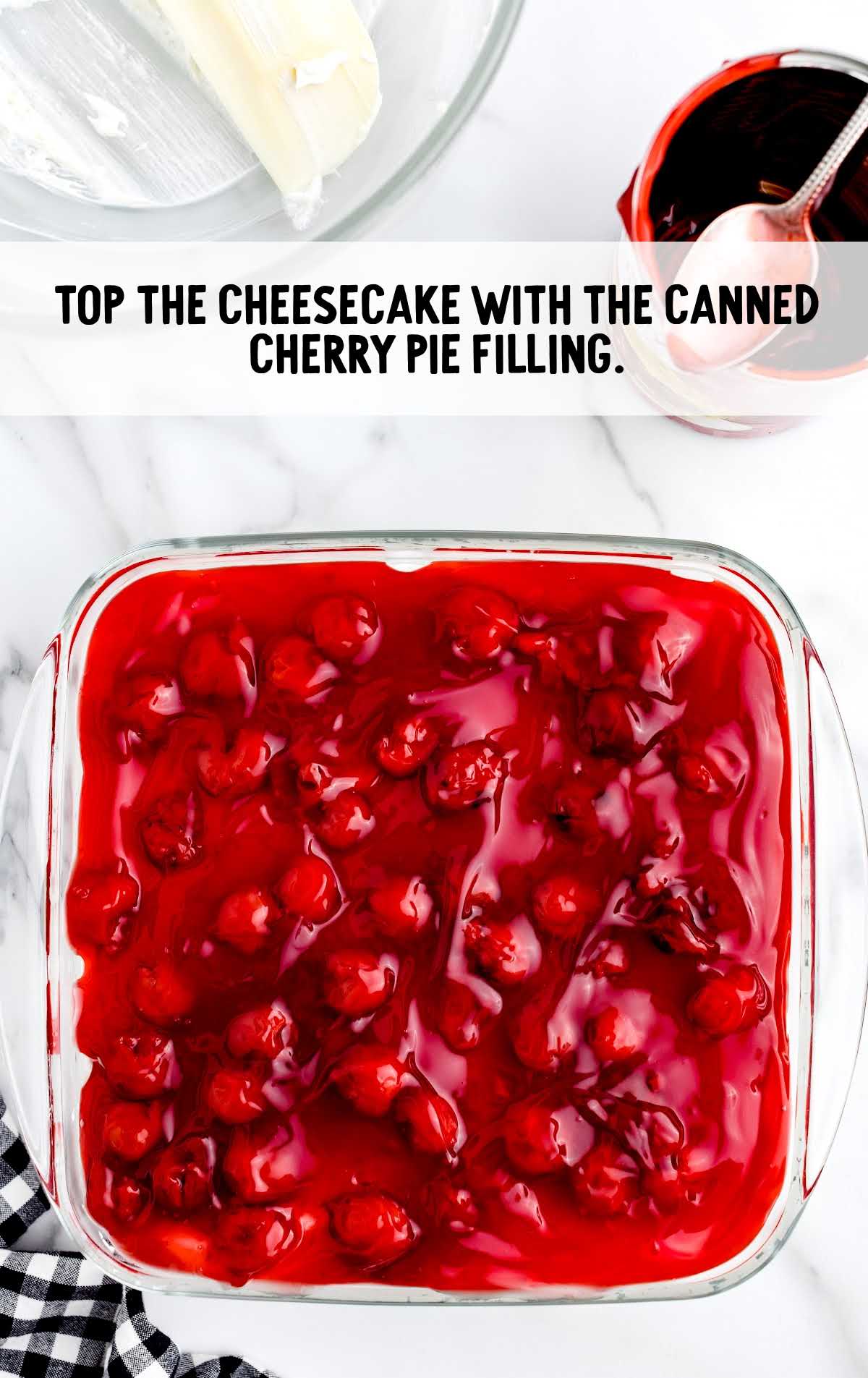 cheesecake topped with canned cherry pie filling in a baking dish