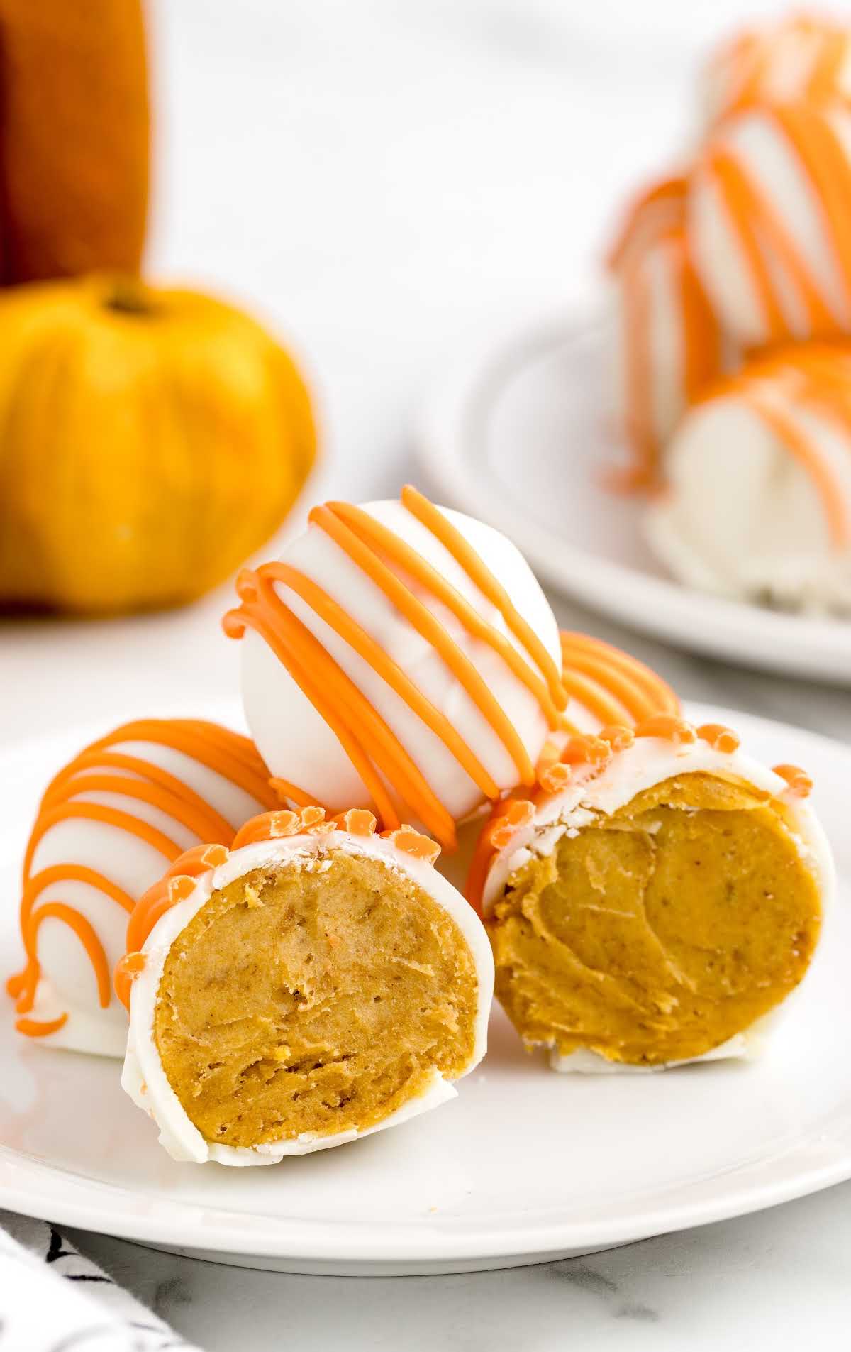 close up shot of No Bake Pumpkin Cheesecake Balls on a plate with one split in half
