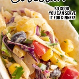 Close-up of a taco filled with shredded chicken and creamy Mexican coleslaw with corn, beans, and peppers.