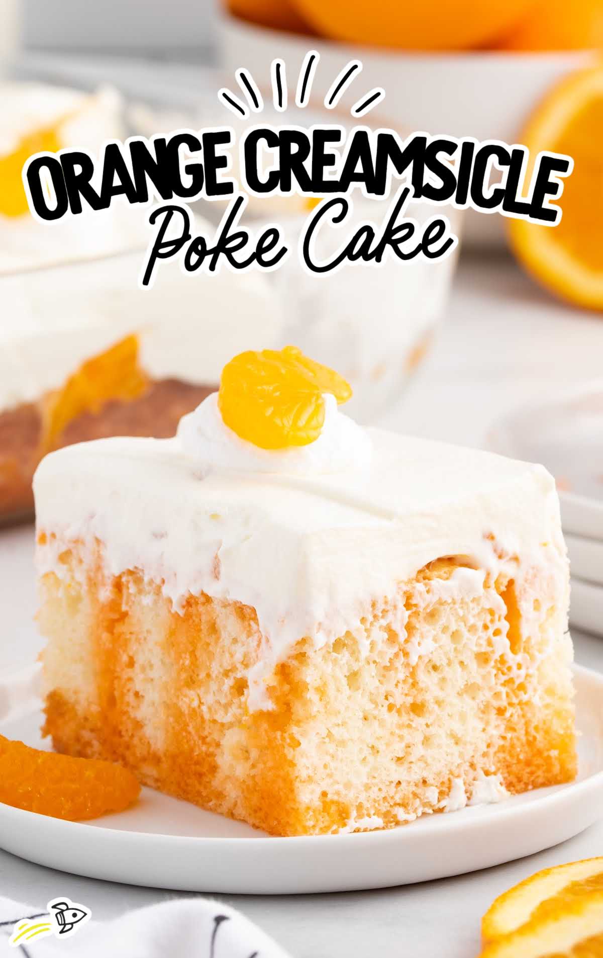 a close up shot of a slice of Orange Creamsicle Poke Cake on a plate topped with a mandarin