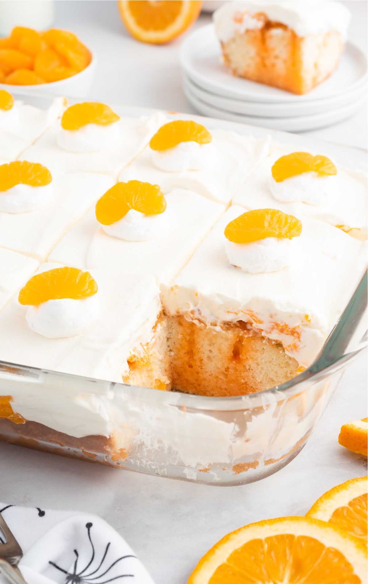 a close up shot of orange creamsicle poke cake in a baking dish with a slice taken out