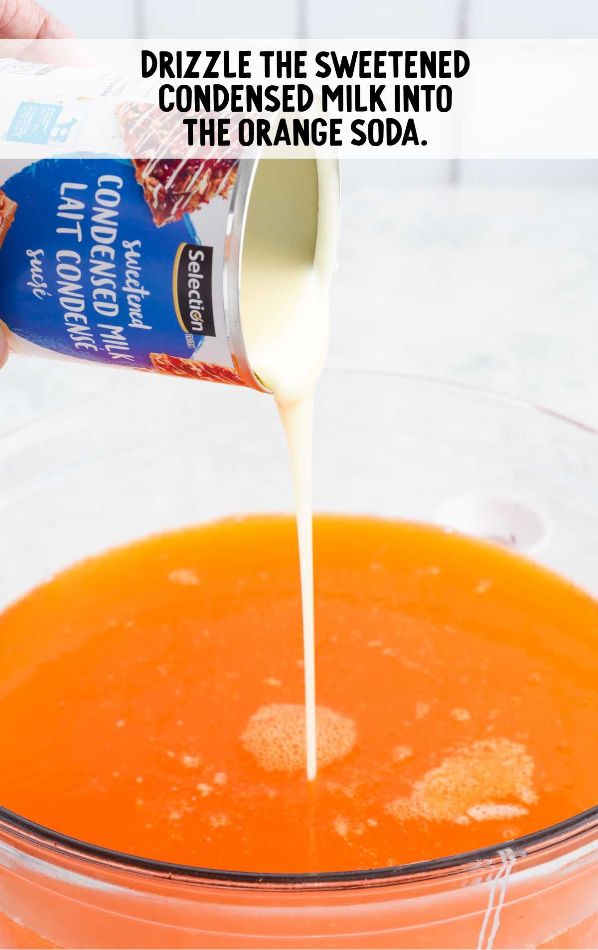 sweetened condensed milk drizzled into the orange soda in a bowl