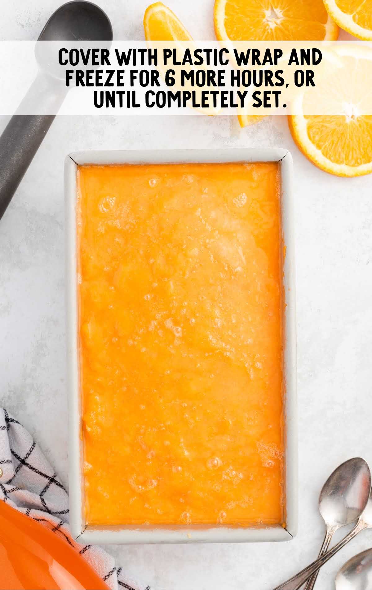 Orange Sherbet mixture in a loaf pan covered with plastic wrap
