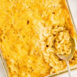 overhead shot of Pumpkin Spice Mac and Cheese in a baking dish with a spoon grabbing a piece