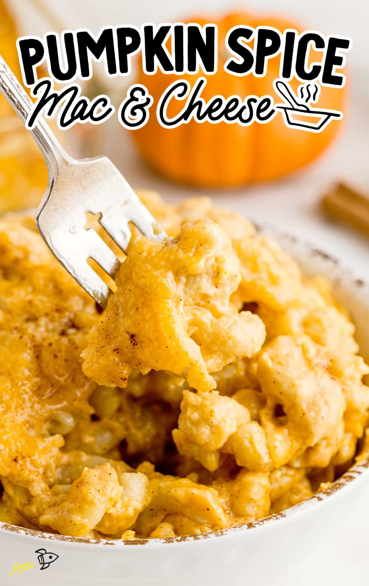 a close up shot of a bowl full of pumpkin spice mac and cheese with a fork grabbing a piece