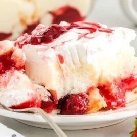 a slice of strawberry cake on a plate with a piece taken out of it with a fork