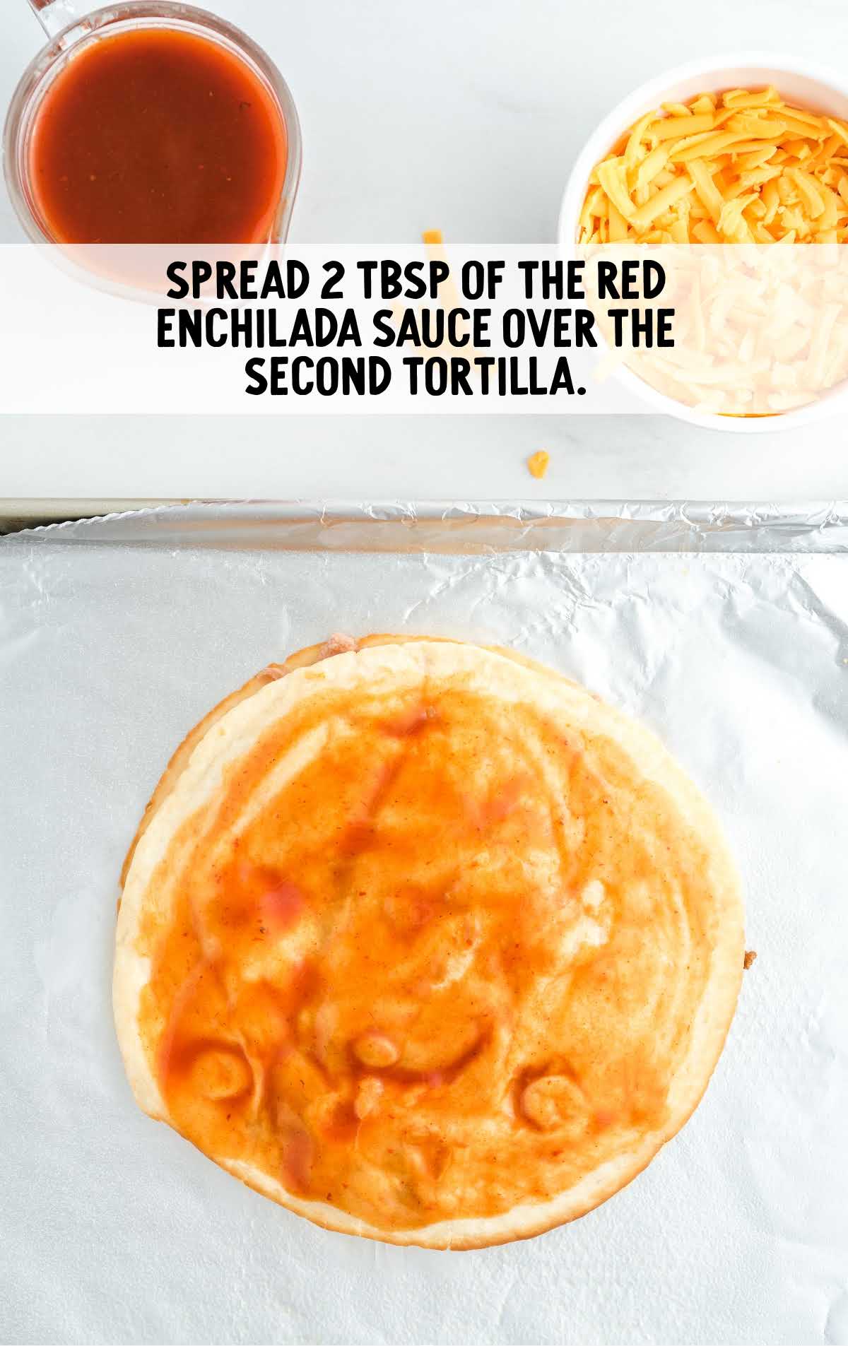 red enchilada sauce spread over the second tortilla