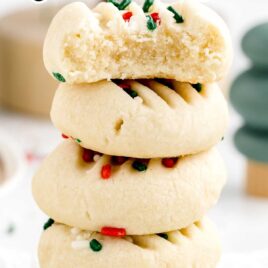 a close up shot of Christmas Shortbread Cookies stacked on top of each other with one having a bite taken out