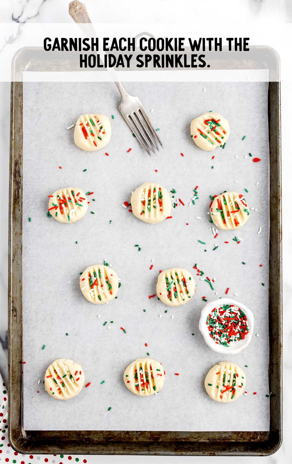 cookies garnished with holiday sprinkles on a cookie sheet