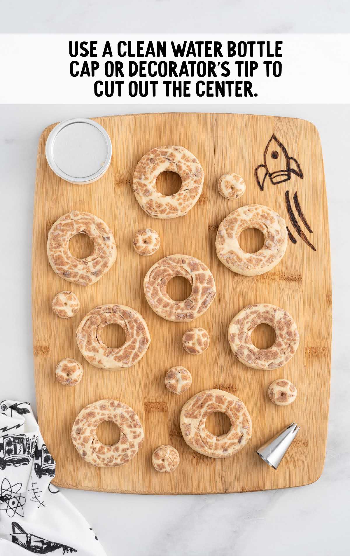 cut out the center of the donut by using a water bottle cap on a wooden cutting board