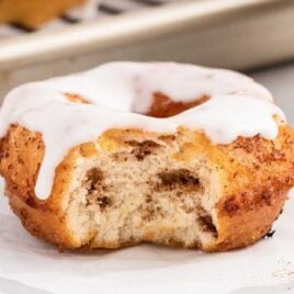 a close up shot of a cinnamon roll donut with a bite taken out of it