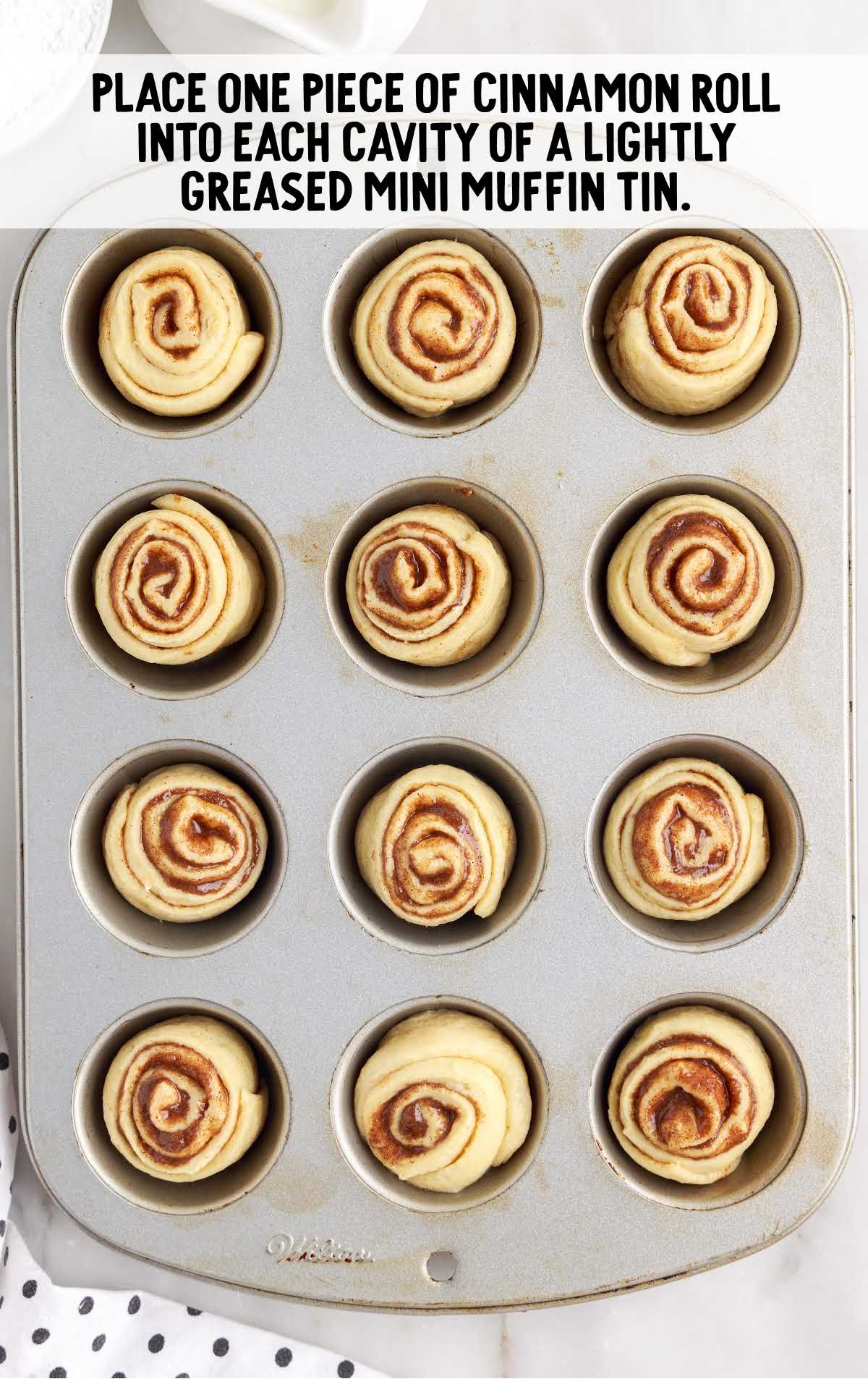 cinnamon roll pieces placed in to each cavity in a muffin pan