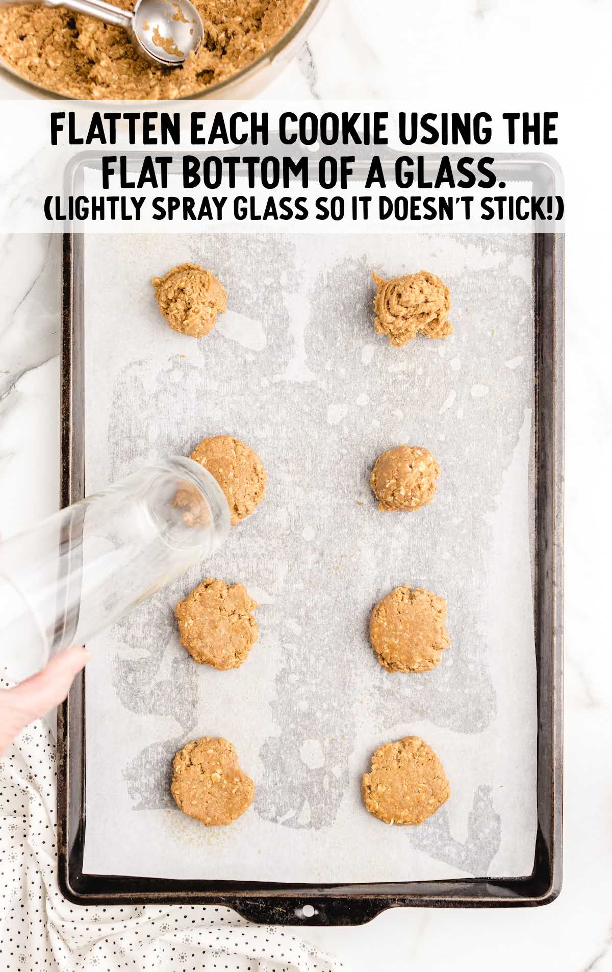 cookies flatten by the bottom of a glass on a cookie sheet