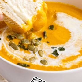 close up shot of Pumpkin Soup in a bowl with bread being dipped in it