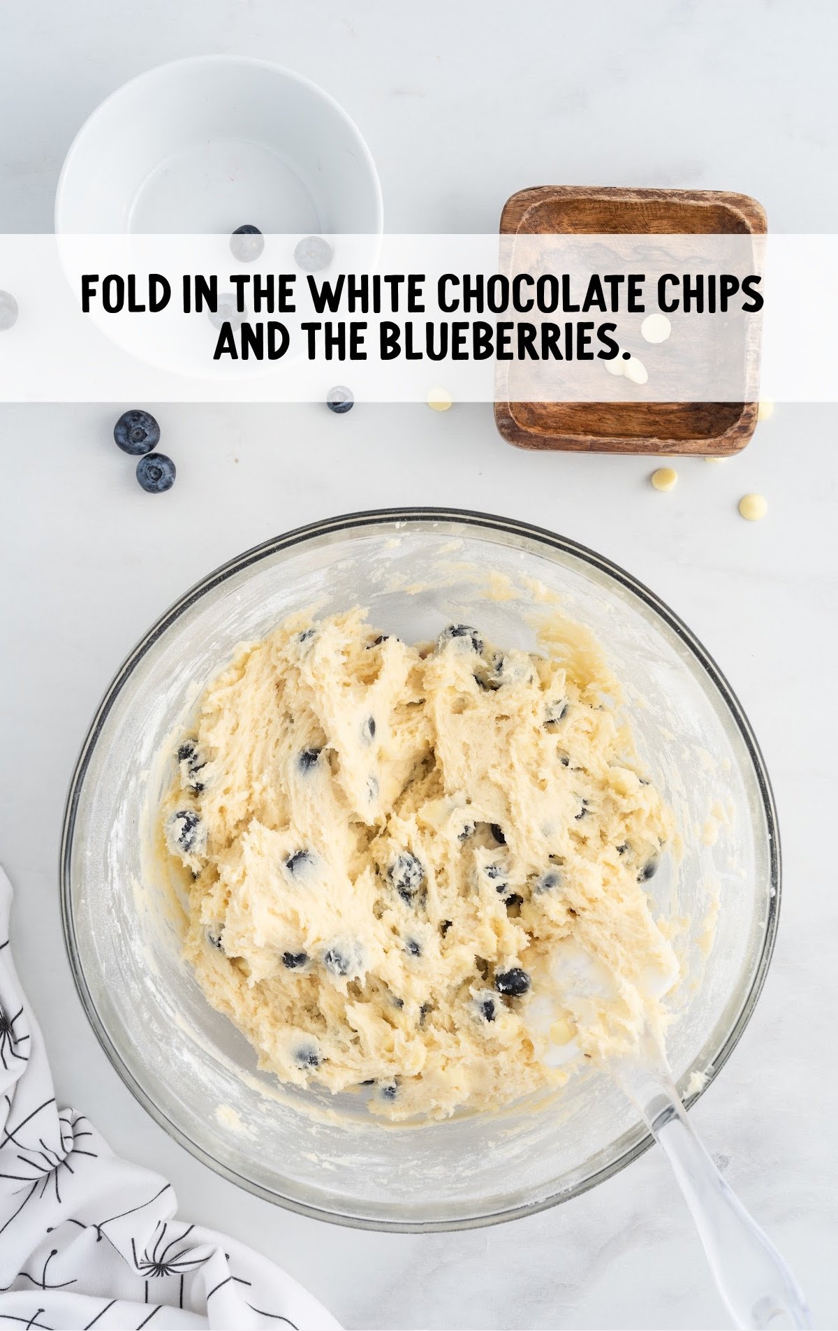 white chocolate chips and blueberries folded with the sour cream mixture in a bowl