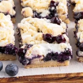 a close up shot of pieces of Blueberry Pie Bars on a parchment paper