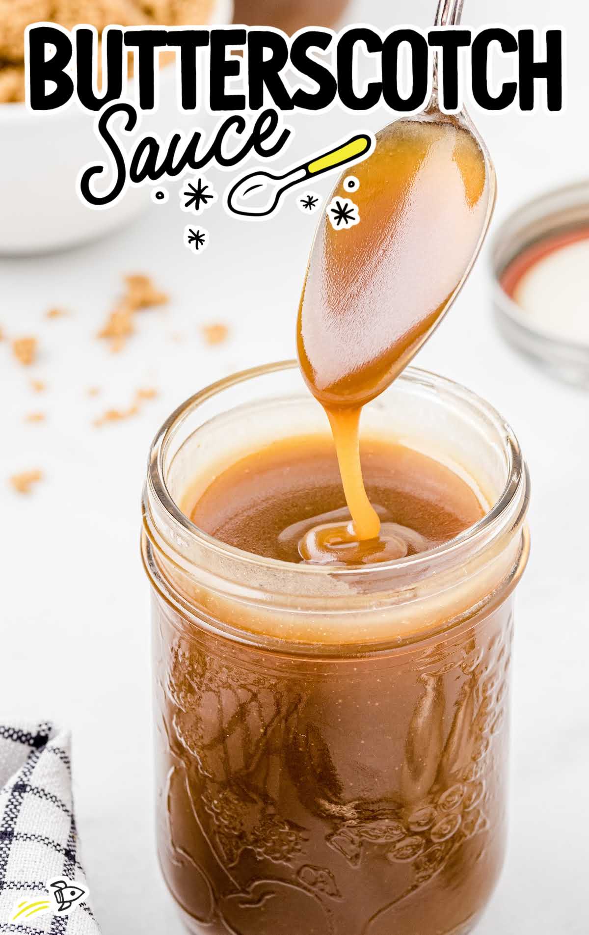 a close up shot of Butterscotch Sauce in a mason jar with a spoon