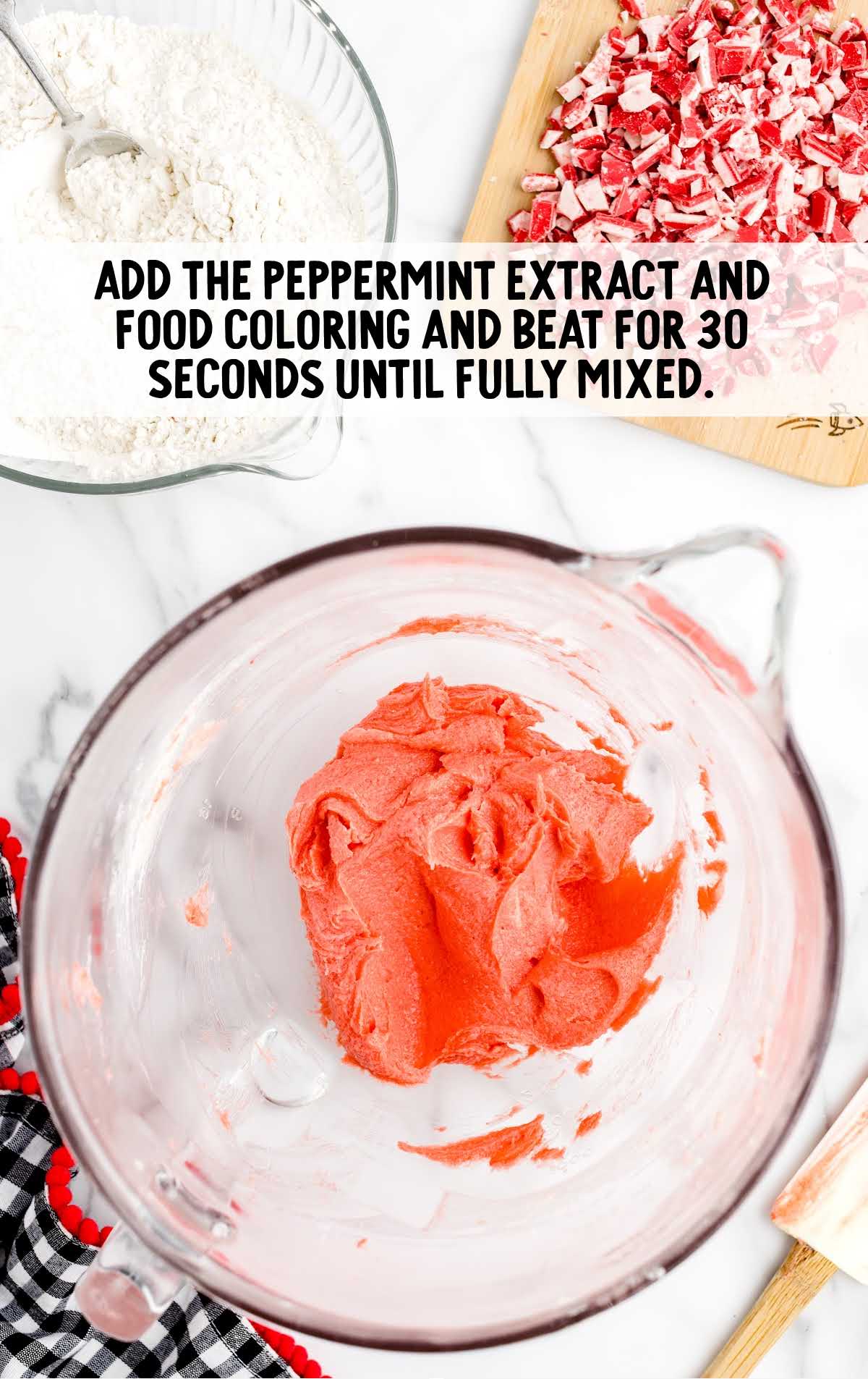 peppermint extract and food coloring added to the butter mixture in a measuring cup