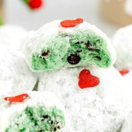a close up shot of Grinch Snowball Cookies with one split in half on a plate