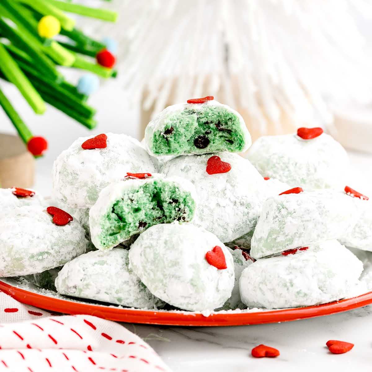 a close up shot of Grinch Snowball Cookies with one split in half on a plate