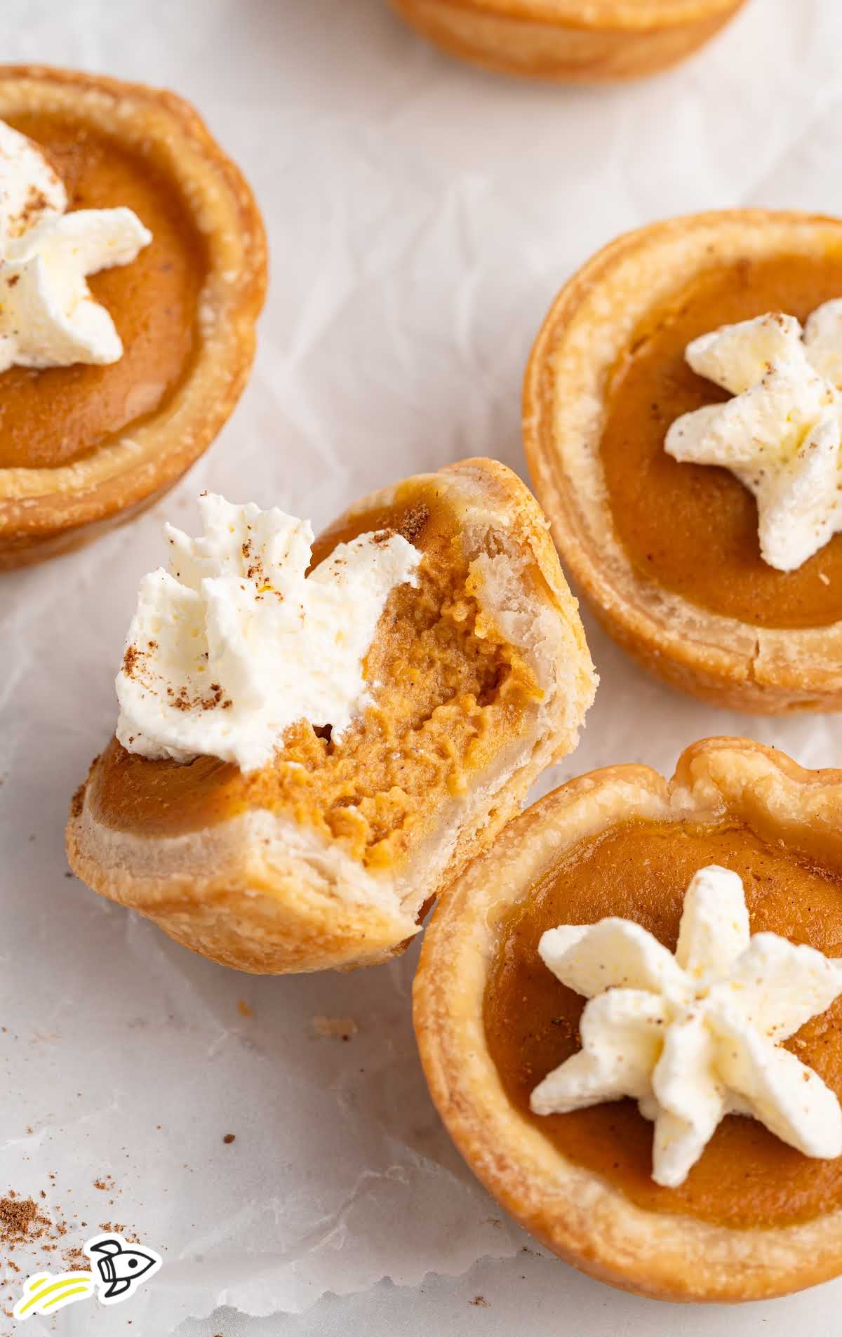 Mini pumpkin pie with a bite taken out, showing creamy filling and flaky crust