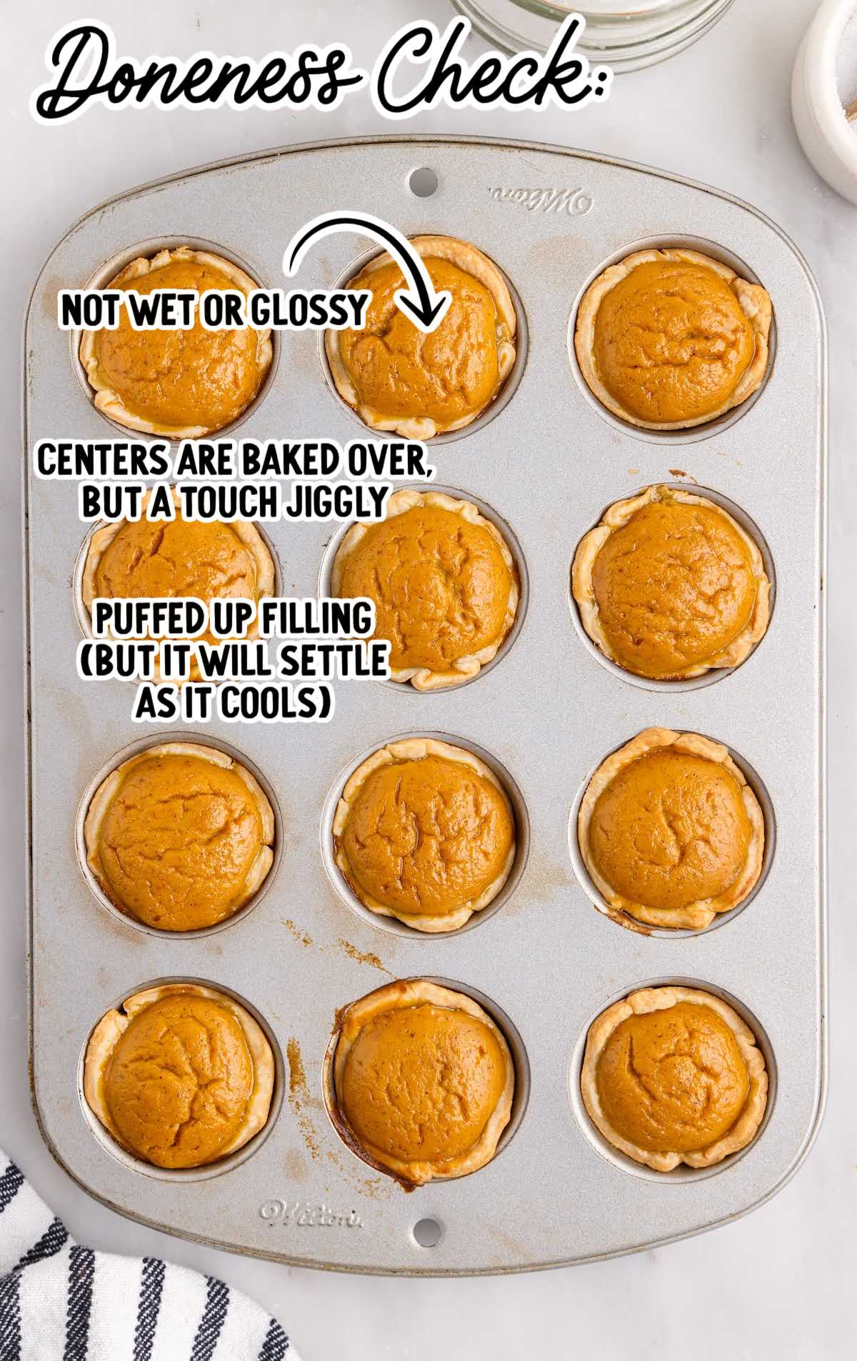 Baked mini pumpkin pies in muffin tin showing doneness check with text annotations
