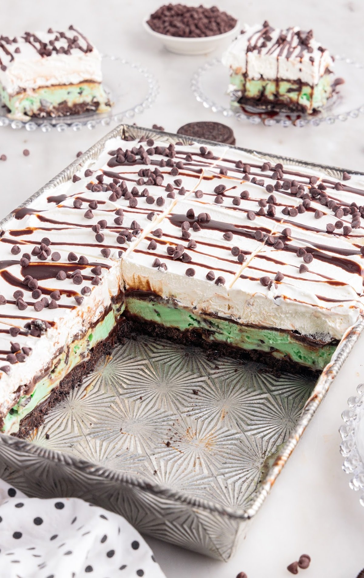 close up shot of a mint chocolate chip ice cream cake in a baking dish with slices taken out