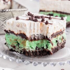a close up shot of a slice of Mint Chocolate Chip Ice Cream Cake on a plate with a bite taken out