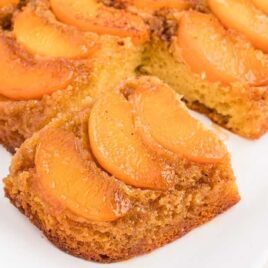 close up shot of Peach Upside-Down Cake in a baking dish with a slice taken out
