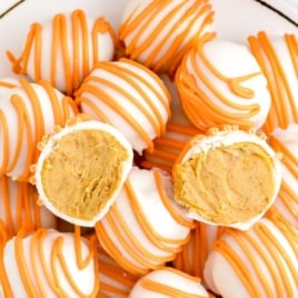 Plate of pumpkin cheesecake balls with creamy pumpkin filling, decorated with orange drizzle
