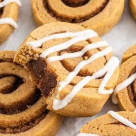 a close up shot of Pumpkin Spice Roll Cookies with one having a bite taken out of it