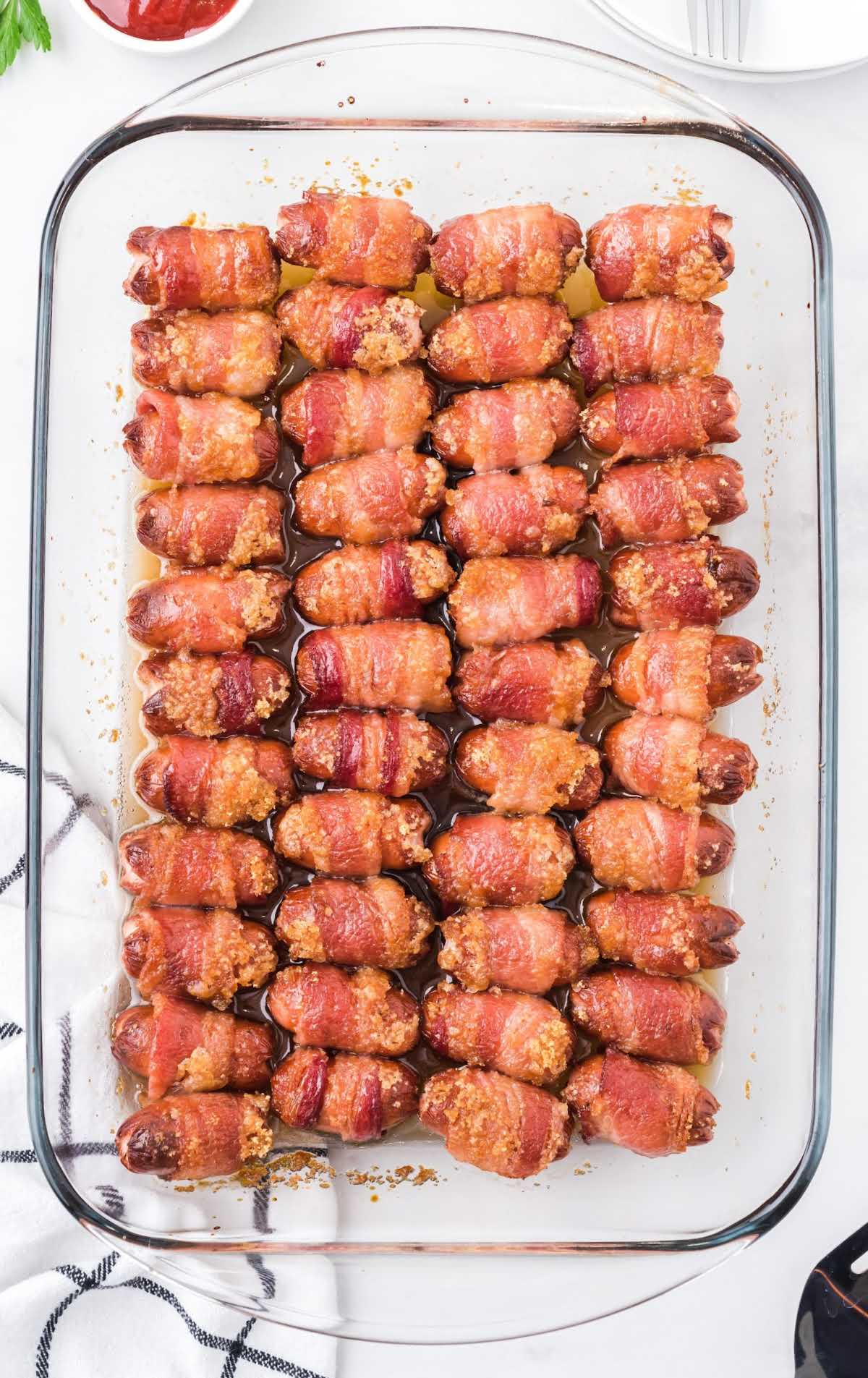 overhead shot of Bacon Wrapped Smokies staked on top of each other in a baking dish