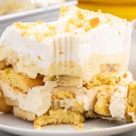 a close up shot of a slice of Banana Delight on a plate with a spoon grabbing a piece