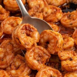 close up shot of Cajun Shrimp in a pan with a spoon grabbing some of them