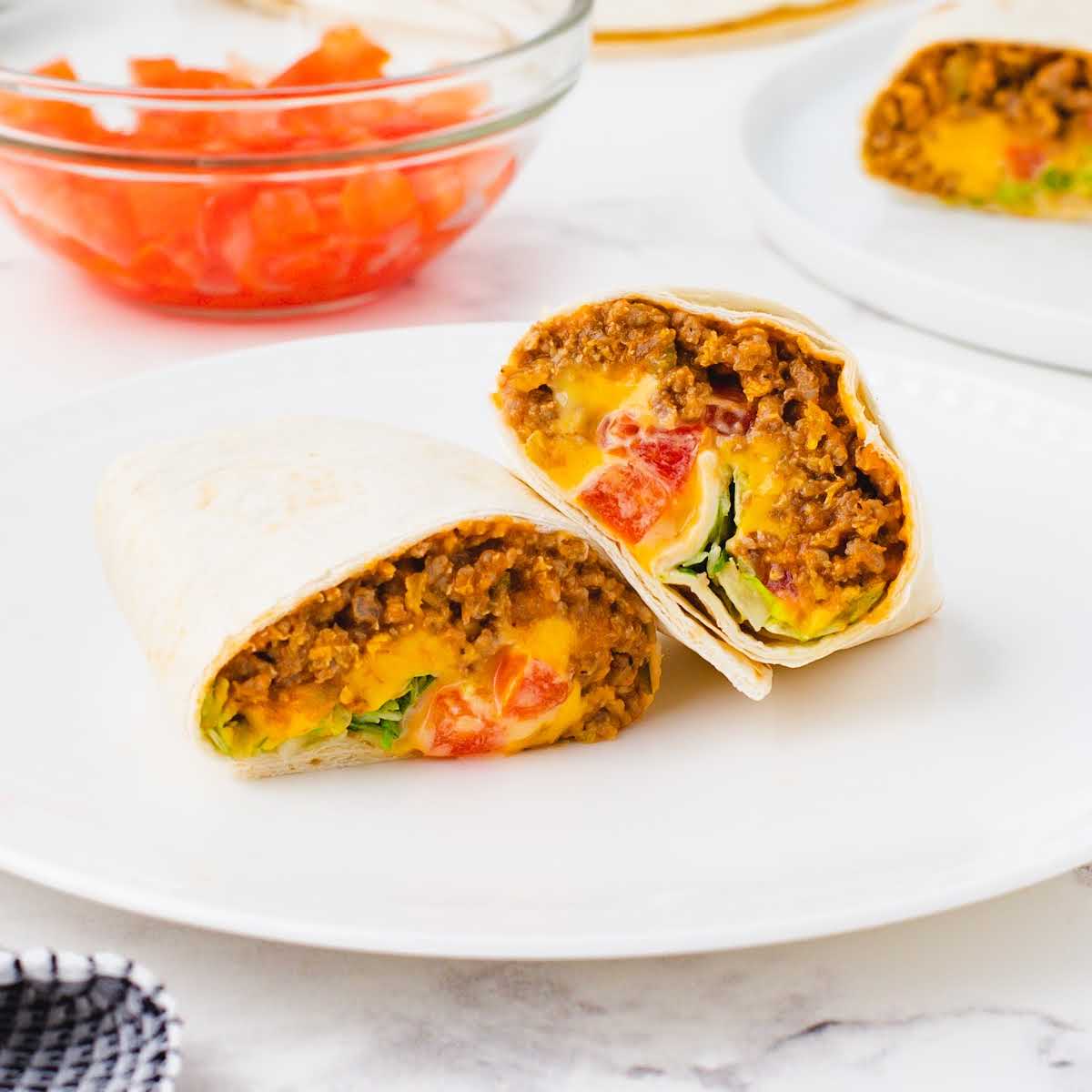 A close up shot of a Cheeseburger Burrito split in half on a plate