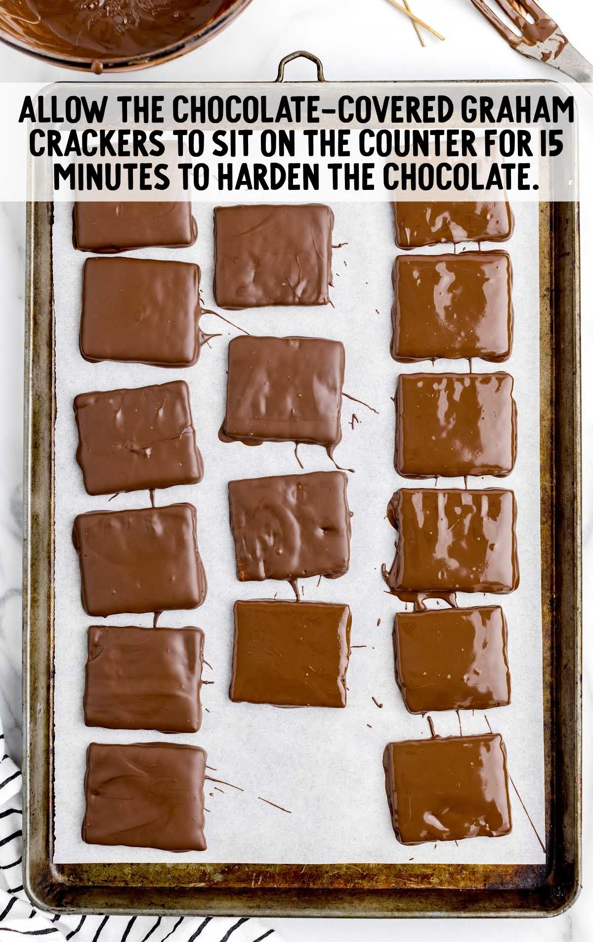 chocolate covered graham crackers sit on a baking sheet