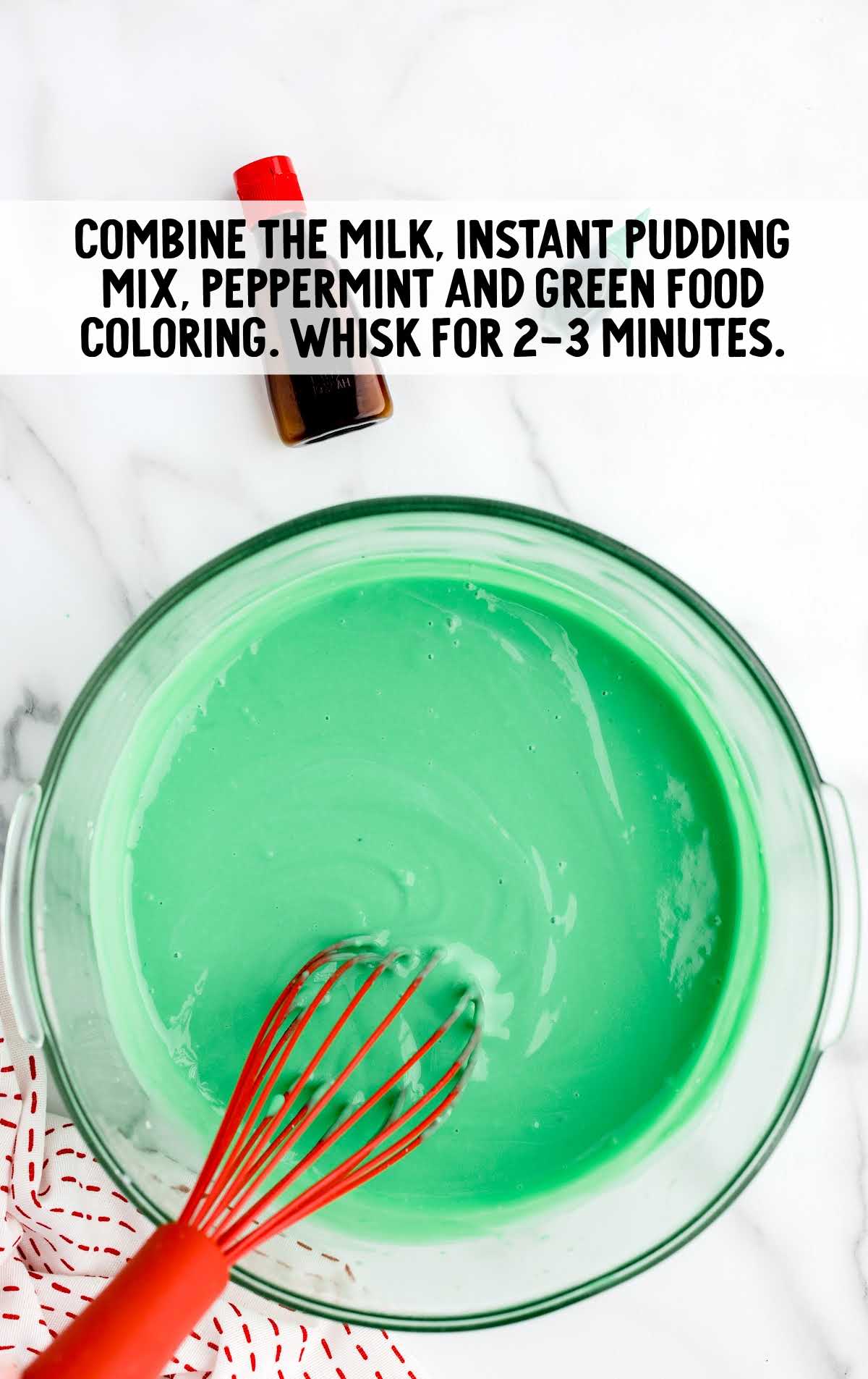 milk, pudding mix and peppermint, green food coloring whisked in a bowl
