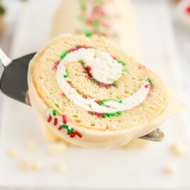 a close up shot of a slice of Christmas Vanilla Roll Cake on a spatula