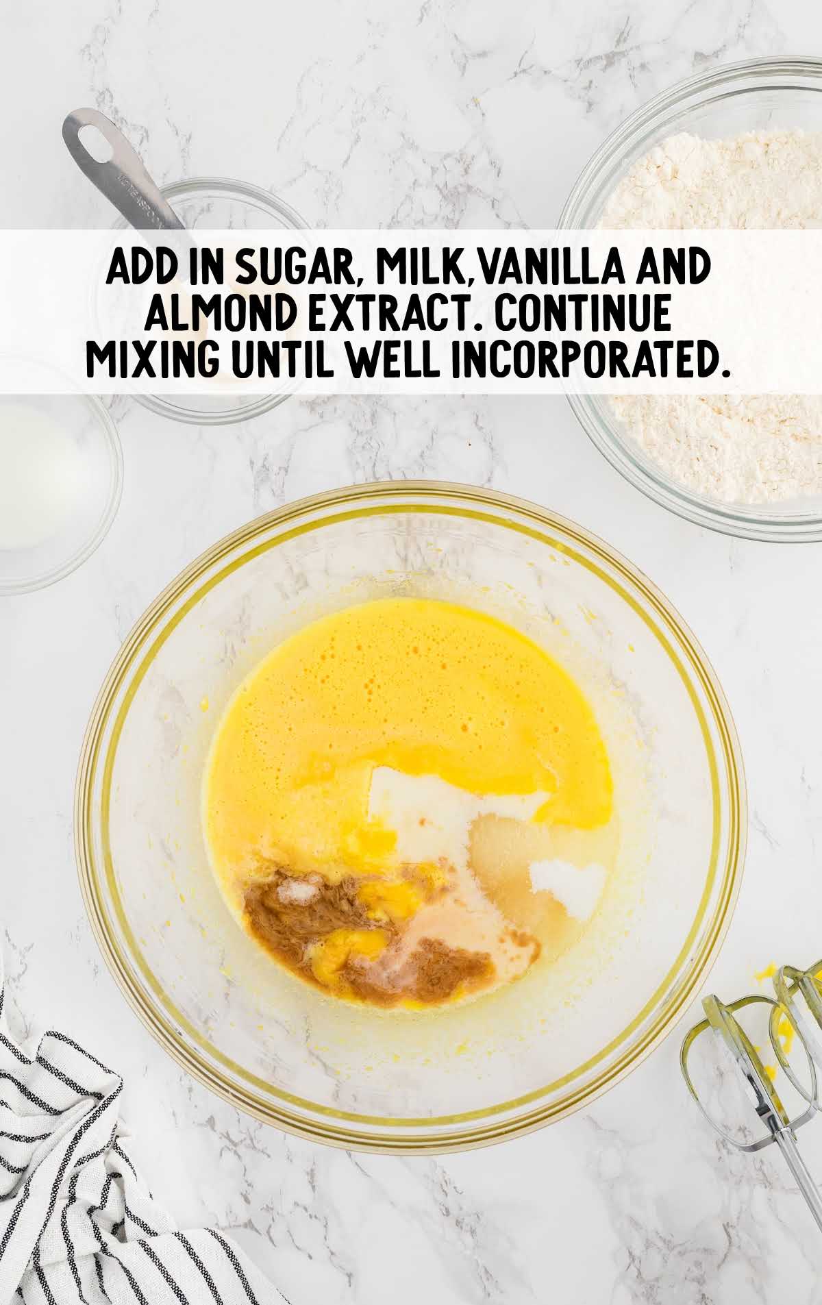 sugar, milk, vanilla and almond extract added to the egg white mixture in a bowl