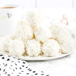 a close up shot of Coconut Snowballs on a plate stacked on top of each other