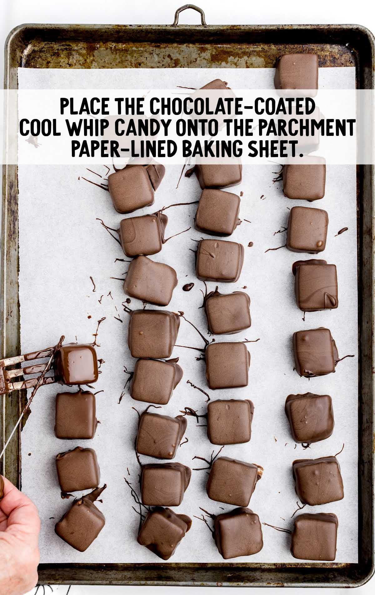 chocolate coated cool whip candy placed onto a parchment paper lined baking sheet