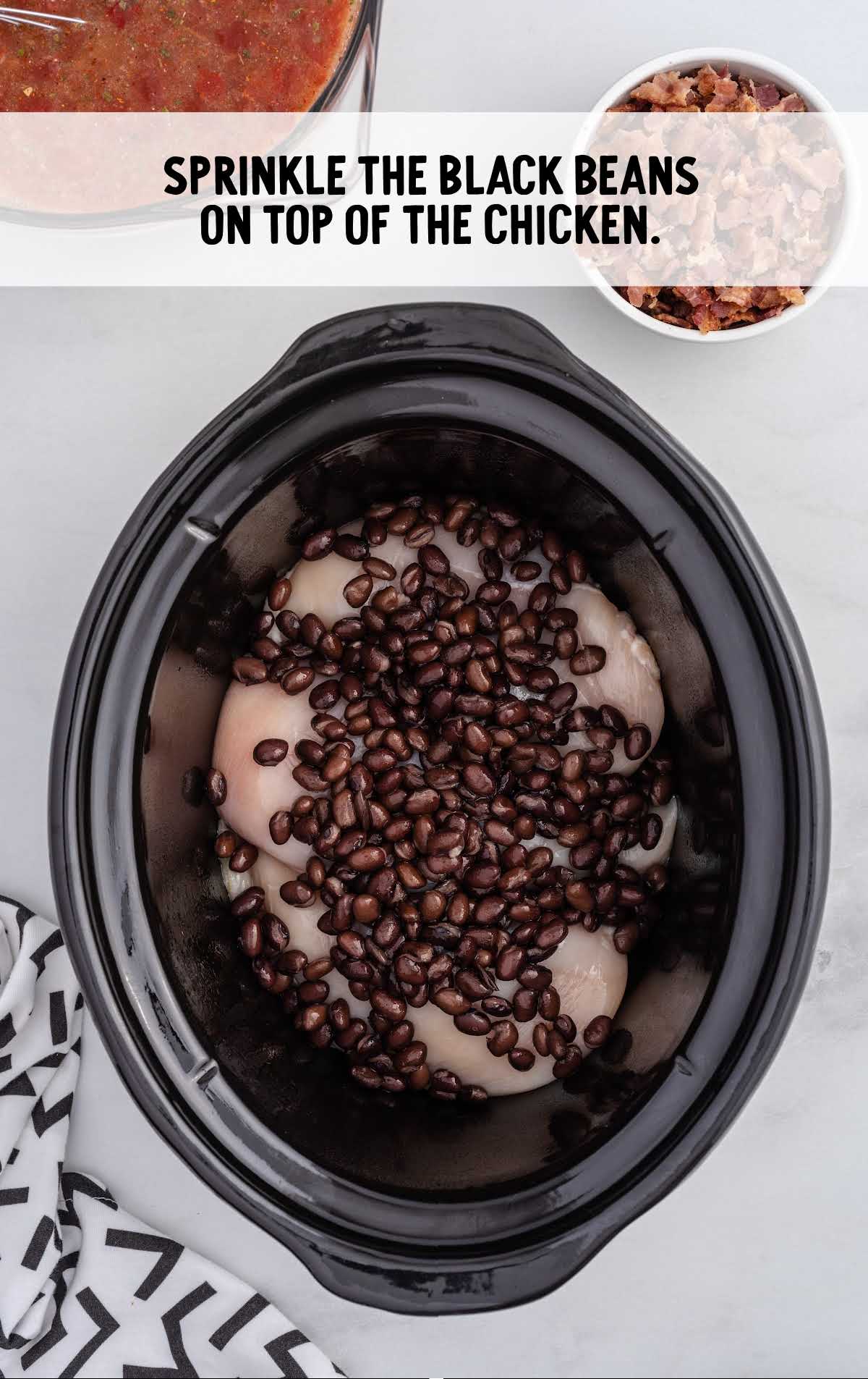 black beans sprinkled on top of the chicken in a crock pot