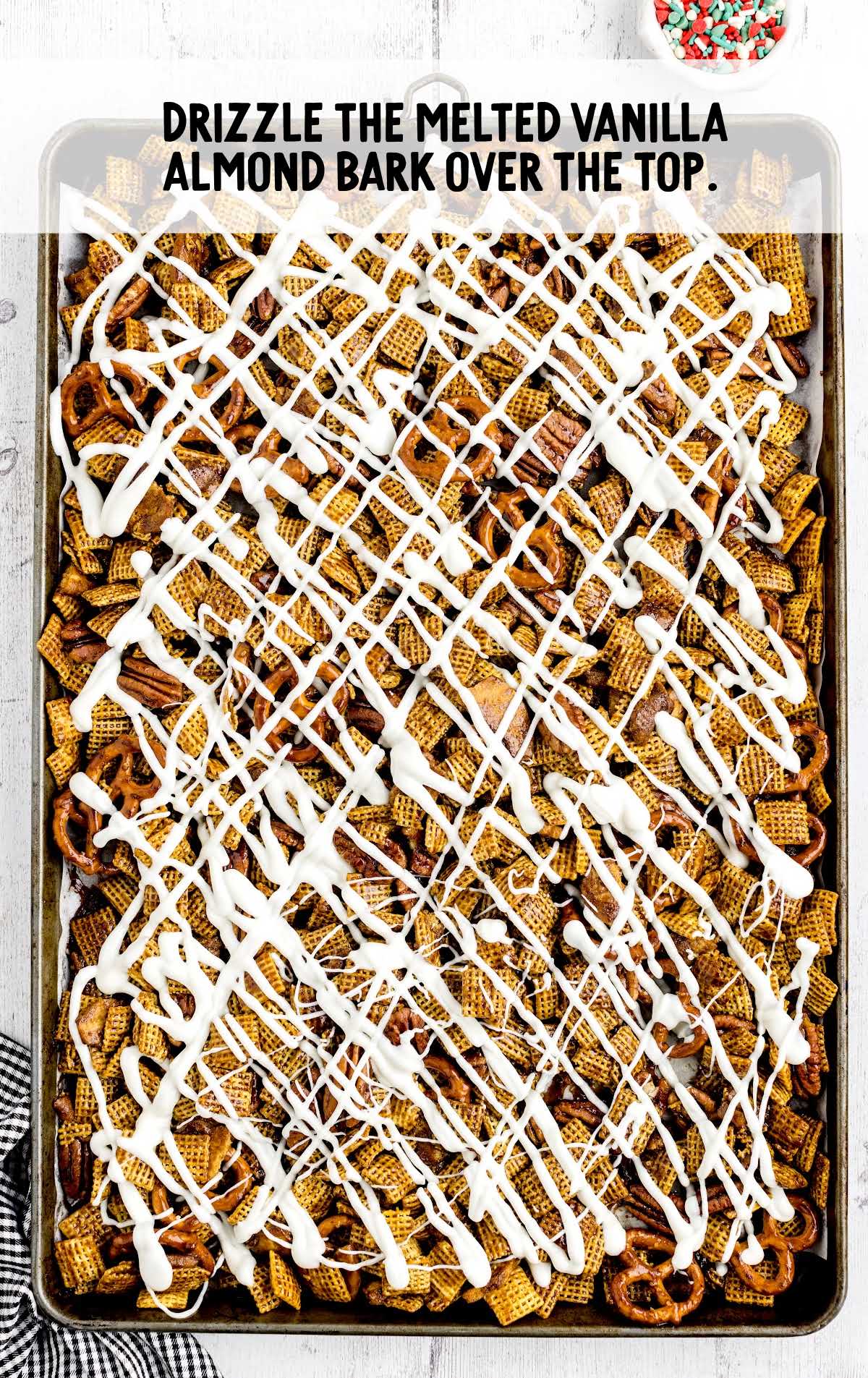 melted vanilla almond drizzled over the top of the chex mix on a baking sheet