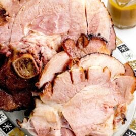 close up shot of ham roast getting cut on a wooden board