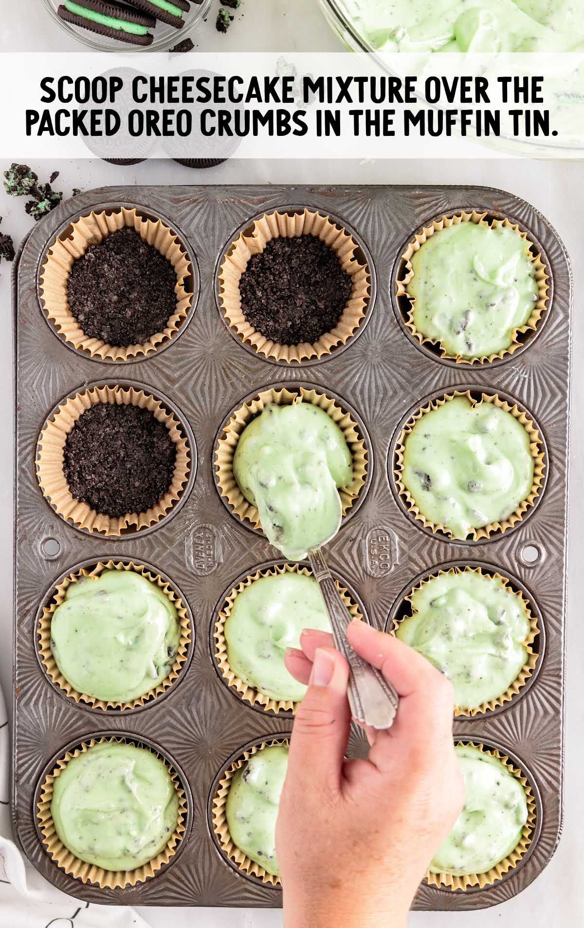 cheesecake mixture scooped over the oreo crumbs in the muffin tin