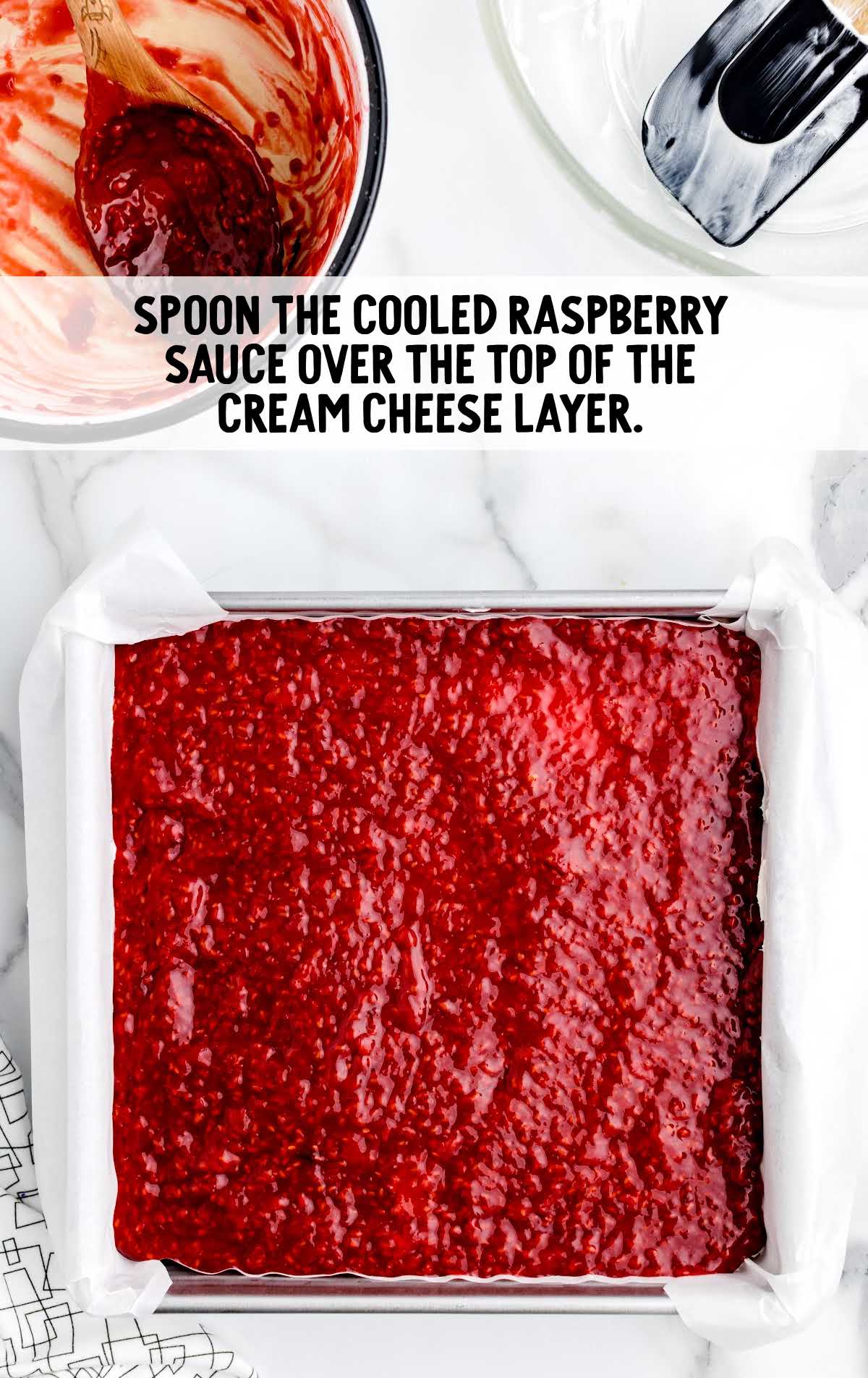 raspberry sauce spooned over the top of the cream cheese layer in a baking dish